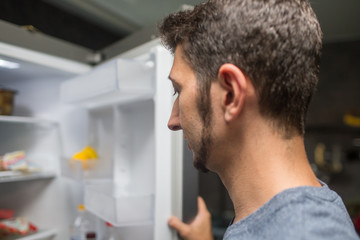 Rear View Of A Young Man Looking At Food Kept In Refrigerator