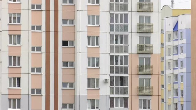 New multi-apartment panel house with glazed loggias and balconies. Frame-panel buildings. The panels are painted white and pink.