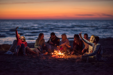 a group of friends enjoying bonfire on beach