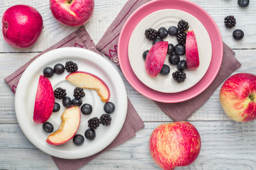 Red apples, blackberries and blueberries in plates