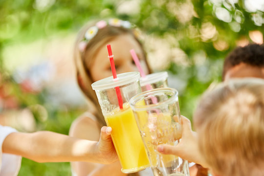 Kinder feiern und sto&szlig;en mit Saft an