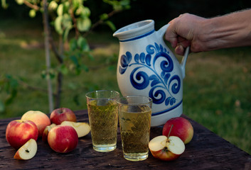 a man's hand pours Traditional apple wine in a refilled glass in the city of Frankfurt. A jug of...