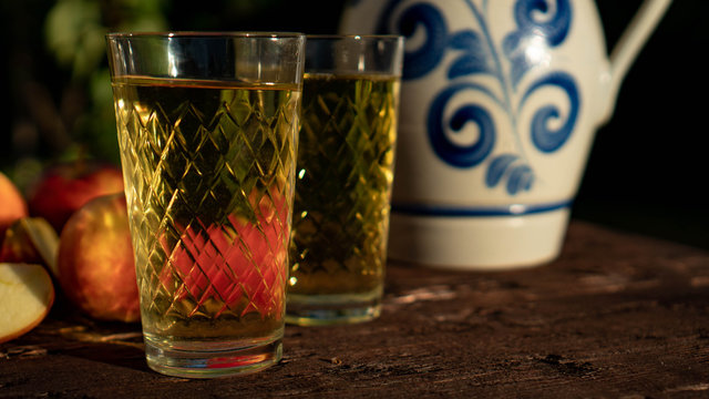Traditional apple wine in the city of Frankfurt in Hesse. A jug of wine is on an old wooden table in the garden, around it are apples