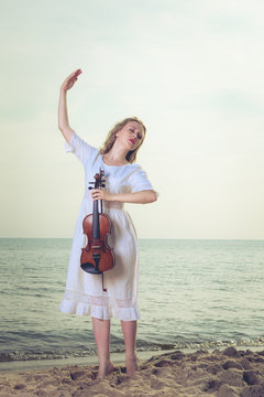 Woman on beach near sea holding violin