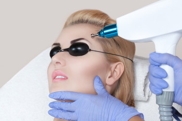 Laser tattoo removal on woman's eyebrows in a beauty salon