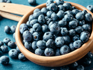 Closeup of fresh blueberry fruit in a wooden plate.