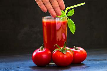 Ripe fresh red tomatoes and a glass of tomato juice in a glass transparent glass, spices, basil....