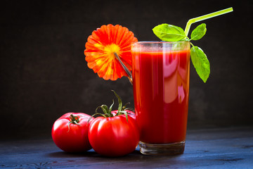 Ripe fresh red tomatoes and a glass of tomato juice in a glass transparent glass, spices, basil....