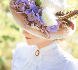 beautiful lady in a hat with flowers in a historic dress smiling