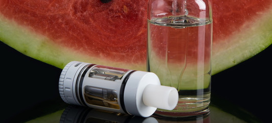 against the background of slices of ripe red watermelon, lie part of the electronic cigarette, with...