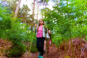 Naklejka na ściany i meble Girl walk in forest with summer camp hiking class