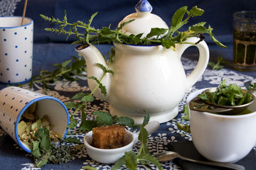 Schöne Teekanne mit Pfefferminztee, Tasse, Becher, Honigwabe und frischer Minze