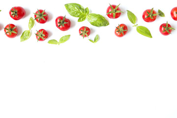 Bunch of juicy organic red cherry tomatoes in row with green basil leaves on white background. Shiny polished glossy vegetables. Clean eating concept. Vegetarian diet. Copy space, flat lay, top view.