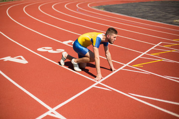 Professional sportsman standing in starting position ready for running  on treadmill of stadium