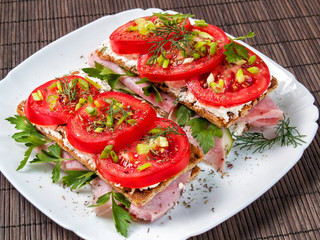 Close-up of sandwiches of their buckwheat loaves, ham, greens, tomato, curd cheese