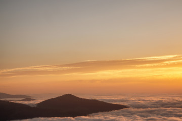 Fototapeta na wymiar Mountain silhouette above the clouds at sunrise, view from the top view of mountains.