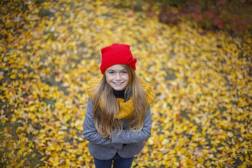 portrait of cute little girl in red hat smiling in beautiful autumn park