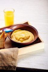 Polenta with butter and some crispy toast. Orange freshly squeezed juice and food on a tray for breakfast in bed. Simple and delicious food for an early morning before work.