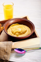 Polenta with butter and some crispy toast. Orange freshly squeezed juice and food on a tray for breakfast in bed. Simple and delicious food for an early morning before work.