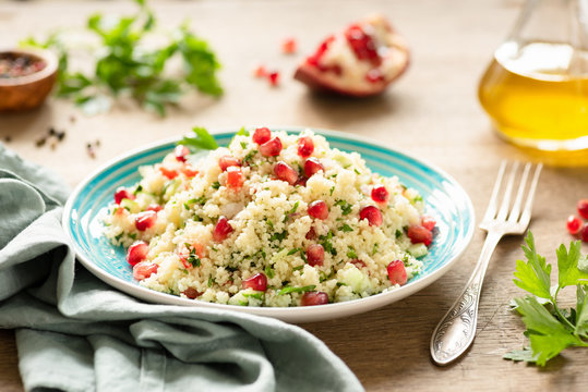 Tabbouleh, Middle Eastern couscous salad with pomegranate, parsley, cucumber on authentic turquoise plate. Vegetarian meal