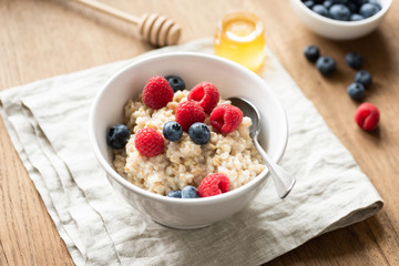 Oats porridge with fresh berries in a bowl, selective focus