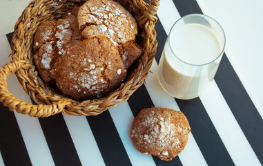 Rustic breakfast with homemade cookies in handmade basket and glass of milk on striped table wear.