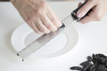Woman grating tonka beans on kitchen table