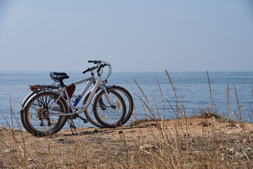 Fototapeta premium Two bicycles on the beach on background a blue sea on a sunny day.