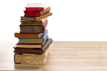 Tower of vintage books with open one on wooden shelf over white background