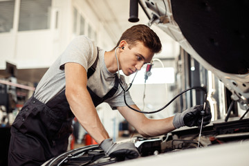 A young but qualified mechanic is conducting a detailed examination of a car