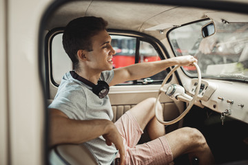 A young and attractive man is driving a vintage car