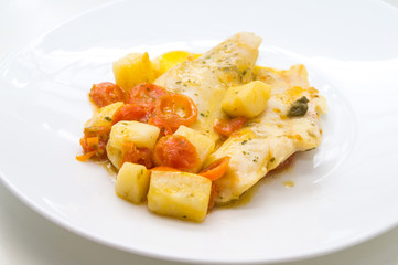 fish dish, cod with tomato, potatoes and capers, cooked in a pan.