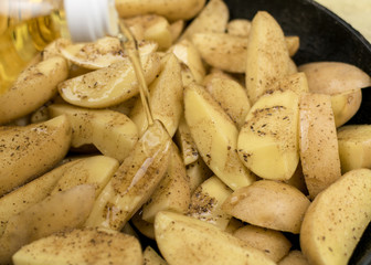 Sliced raw potatoes in a frying pan watered with oil.