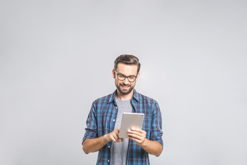 Happy young man in plaid shirt standing and using tablet over grey background - 216569689