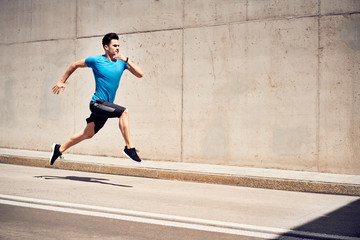 Health and fitness concept. Man doing sprinting and jumping exercises during workout session in the...