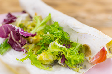Preparation of a roll of pita bread and fresh vegetables on a wooden background. The concept of healthy eating.
