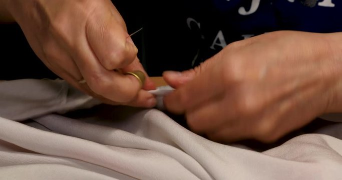 Woman with thimble sewing needle and thread white fabric