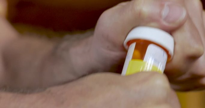 Man struggling and having difficulty opening a pill bottle - close up