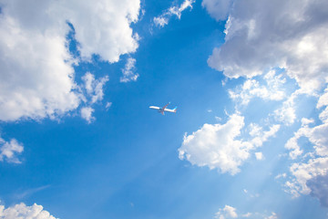 the plane flies in a blue sky against a background of clouds