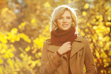 Young blond fashion woman in classic beige coat walking outdoor