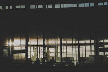 Black sillhouettes of people waiting for their train on a subway station behind glass windows...