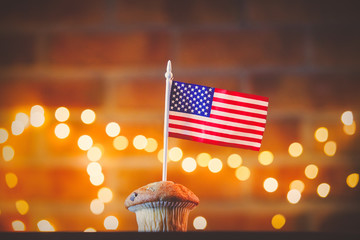 Homemade classic cupcake and flag of the United States with fairy lights in bokeh.