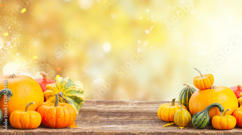 pile of orange pumpkins on wooden table over fall background banner