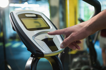 Close-up of simulator screen exploited for training in gym. Guy is pushing button of treadmill for...