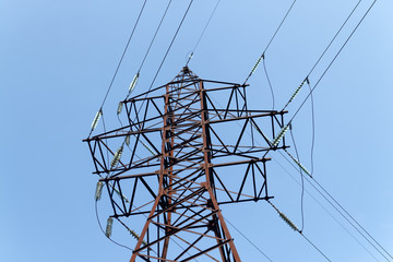 Electric pylon against the backdrop of the blue sky on a summer day