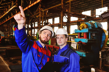 Two industrial workers in construction helmets discuss the project