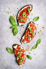 Rye toasts with soft cheese, tomatoes, pine nuts and pesto sauce. Top view with copy space.