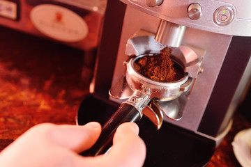 Holder with ground coffee close-up in the hands of baristas or coffee bartenders