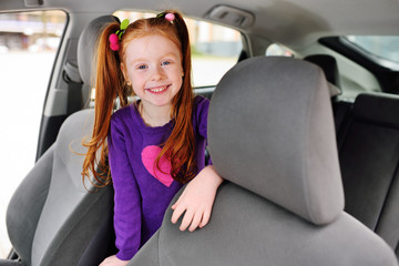 baby cute red-haired girl smiling in car salon