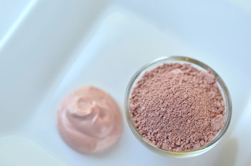 Deep cleansing cosmetic bentonite (montmorillonite) clay for beauty spa face mask, body detox and hair treatments. Clay and activated charcoal powder and mask in glass bowl.
